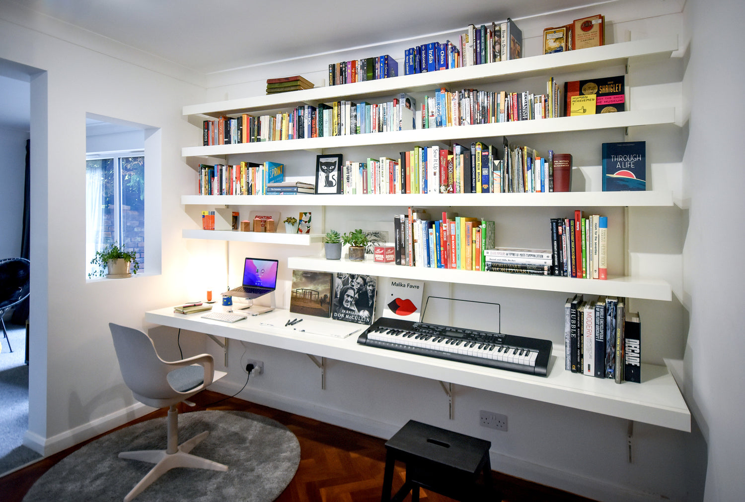 home office with large floating wall desk and long seamless shelves above