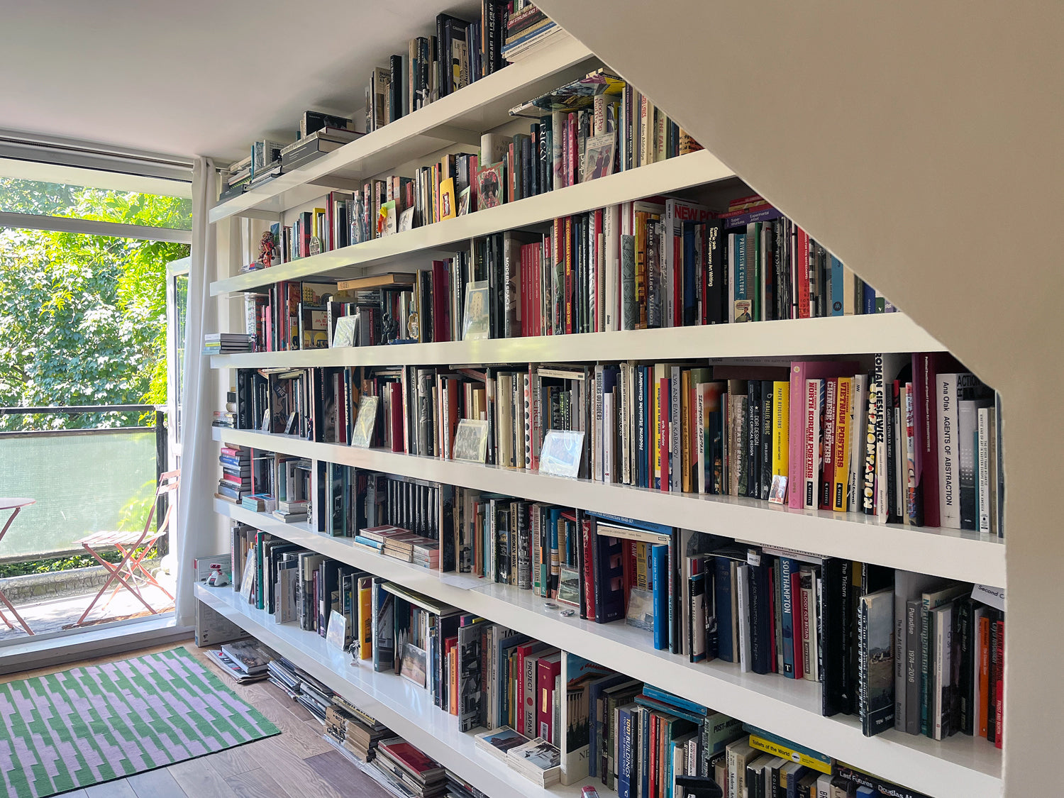 Large wall of heavy books on long white wall shelves