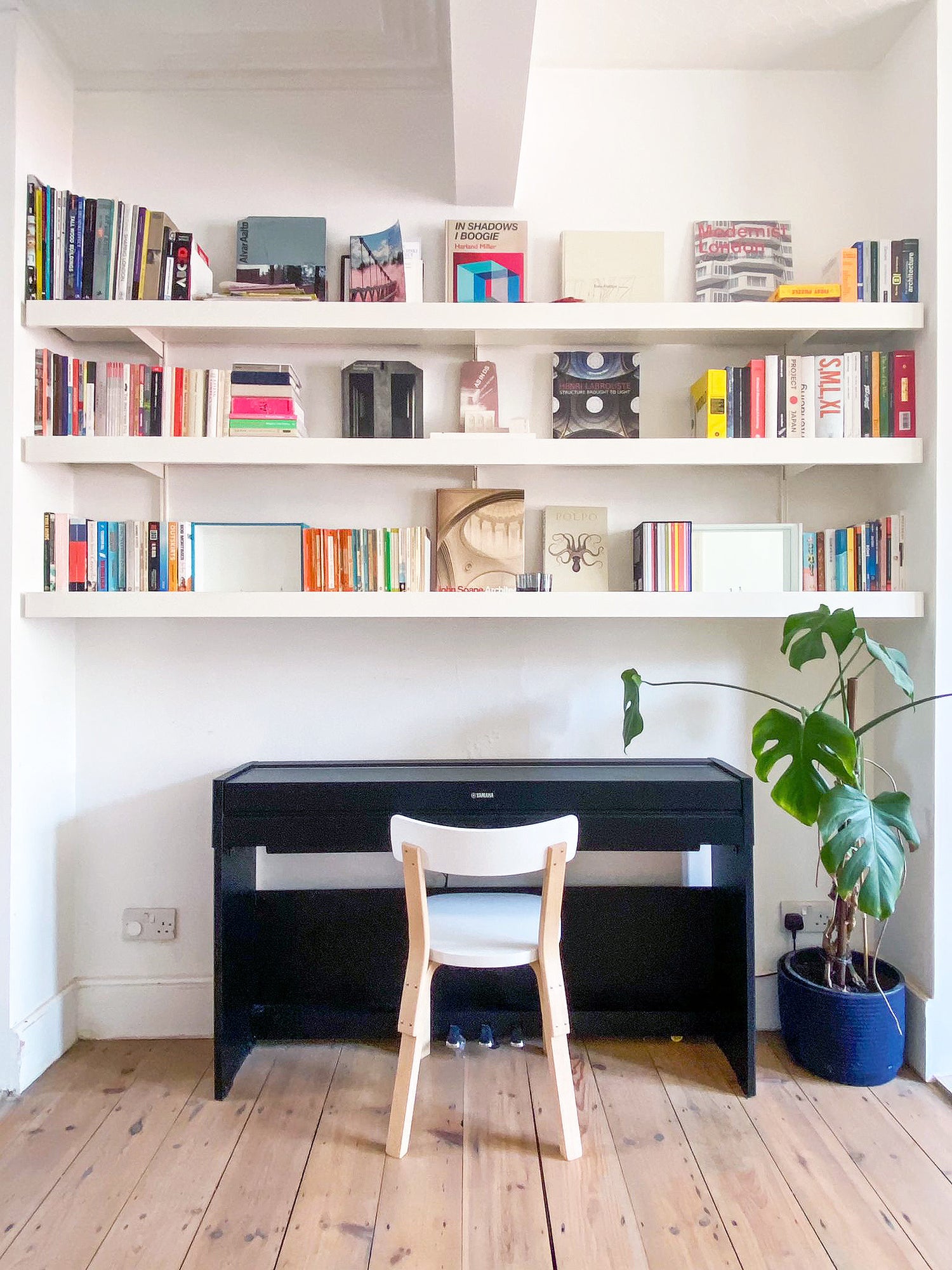 Long white wall shelves mounted above piano and chair