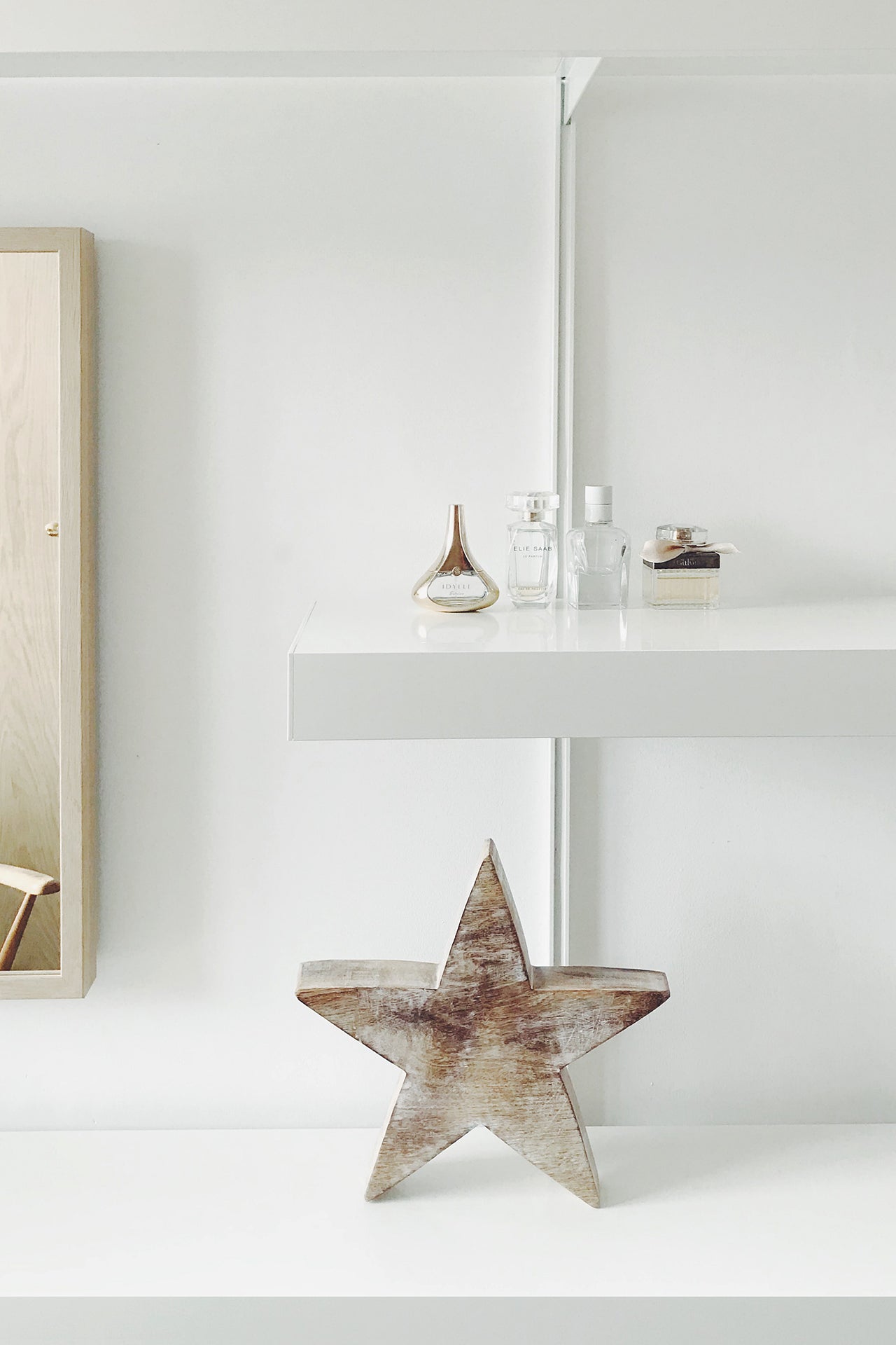 White shelving system detail with mirror and perfume bottles 