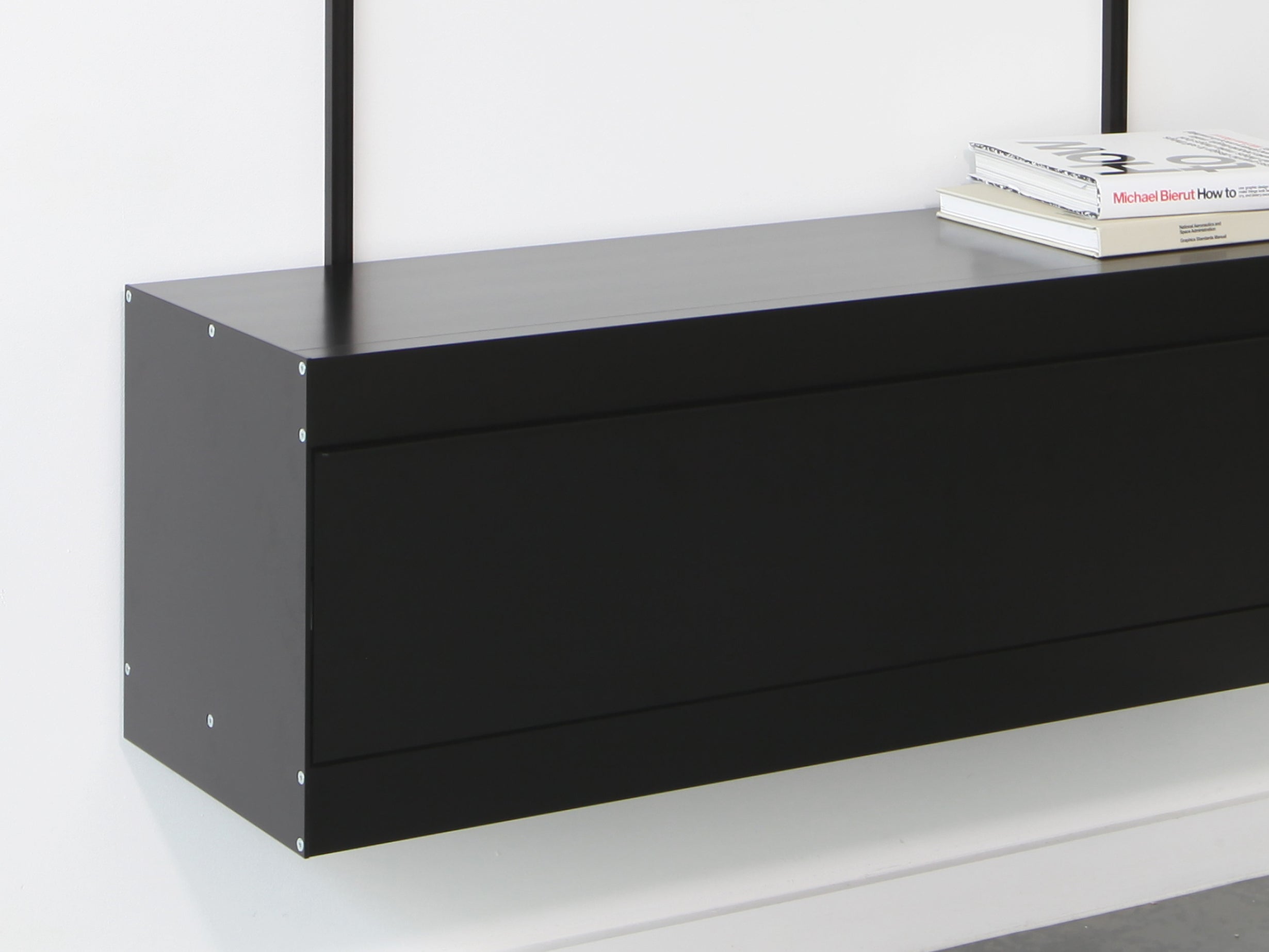 black shelving system with detail of black wall cabinet with fold down door
