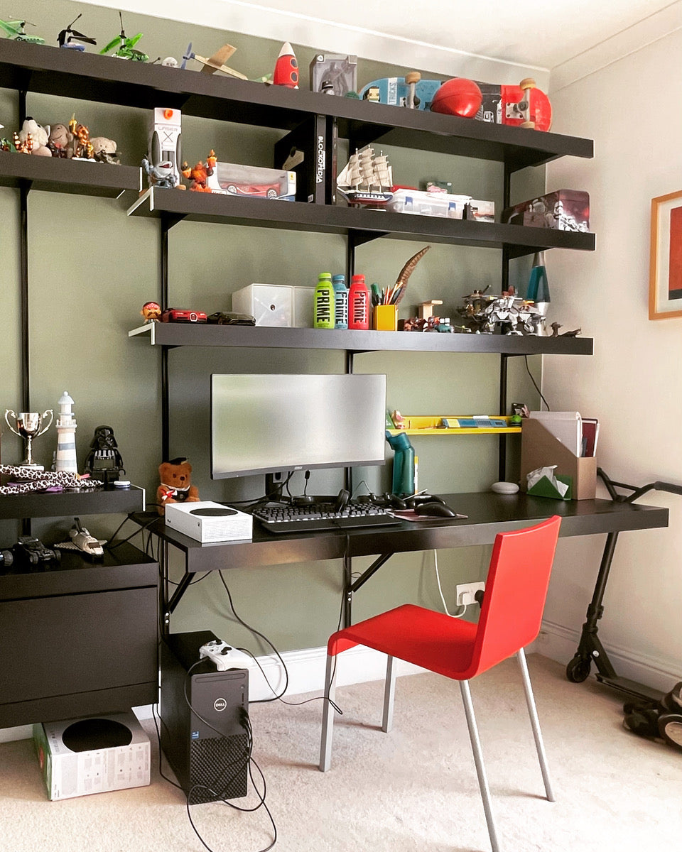 black shelving system with desk and storage in bedroom