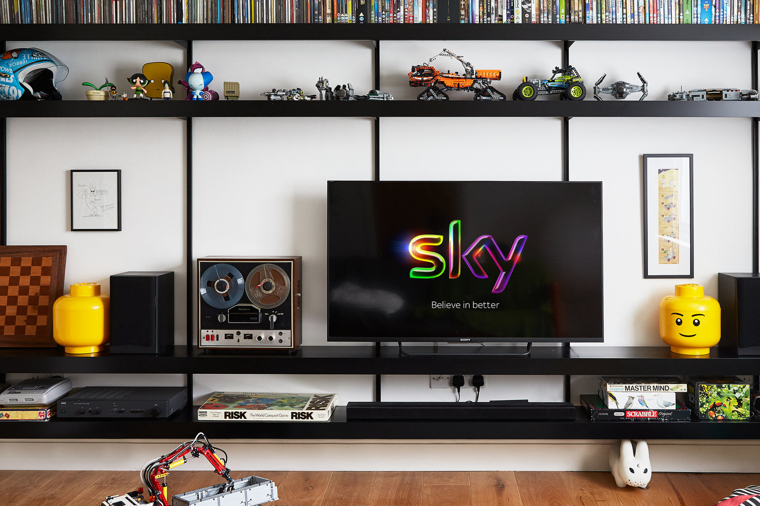 TV shelving system with black wall shelves mounted on white wall