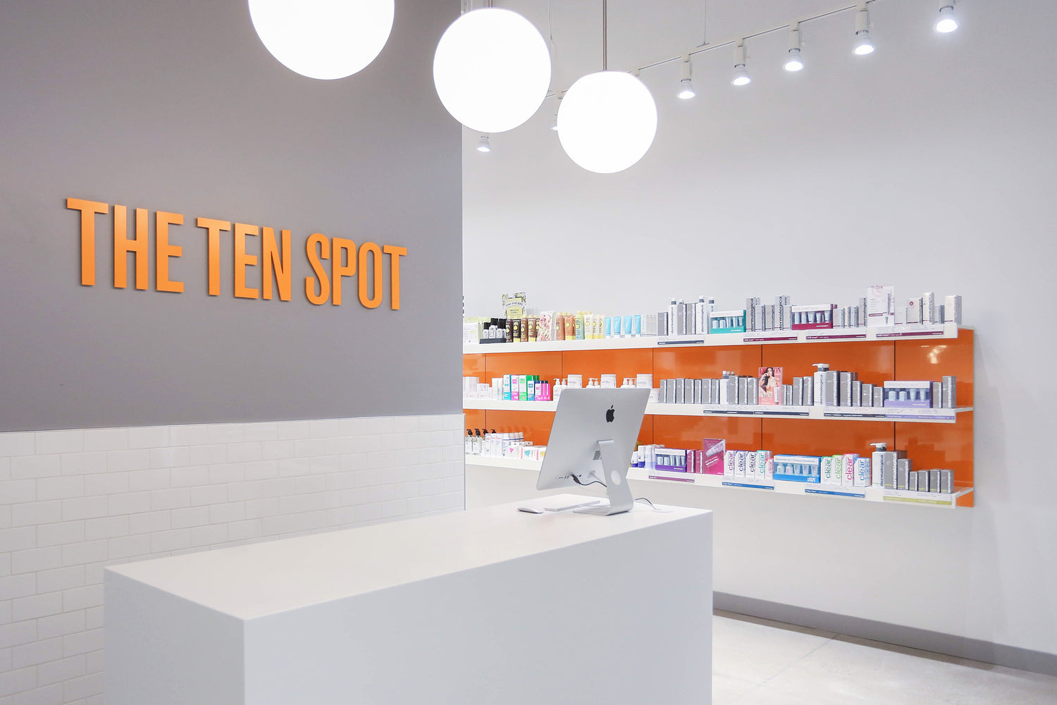 Retail beauty bar reception with long white wall shelving