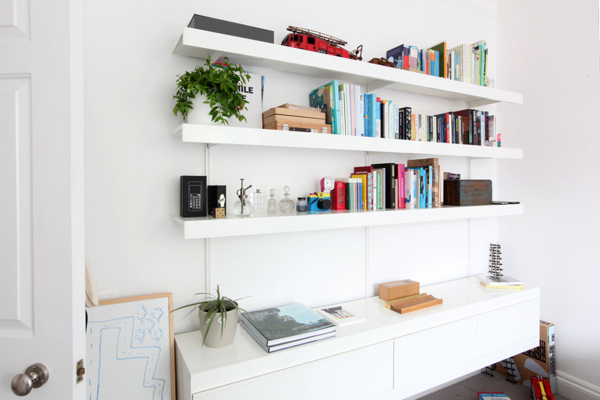 Bedroom shelving system with long seamless shelves and white wall cabinet below