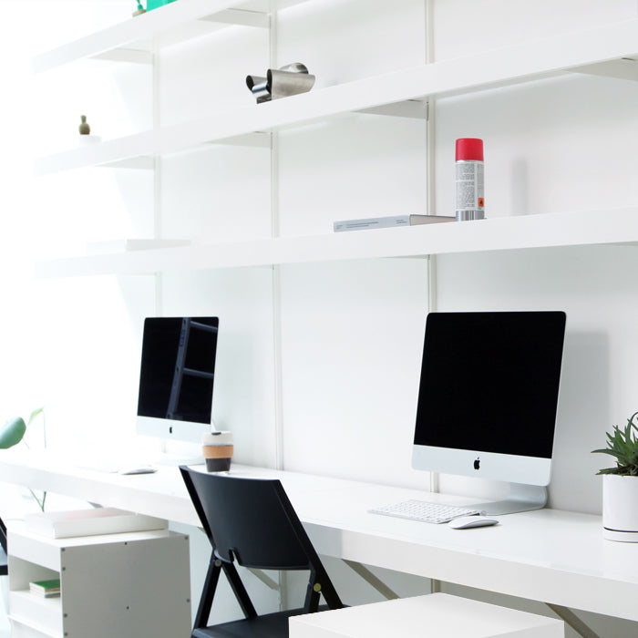 large floating desk with shelves above in office with two computers and shelves above