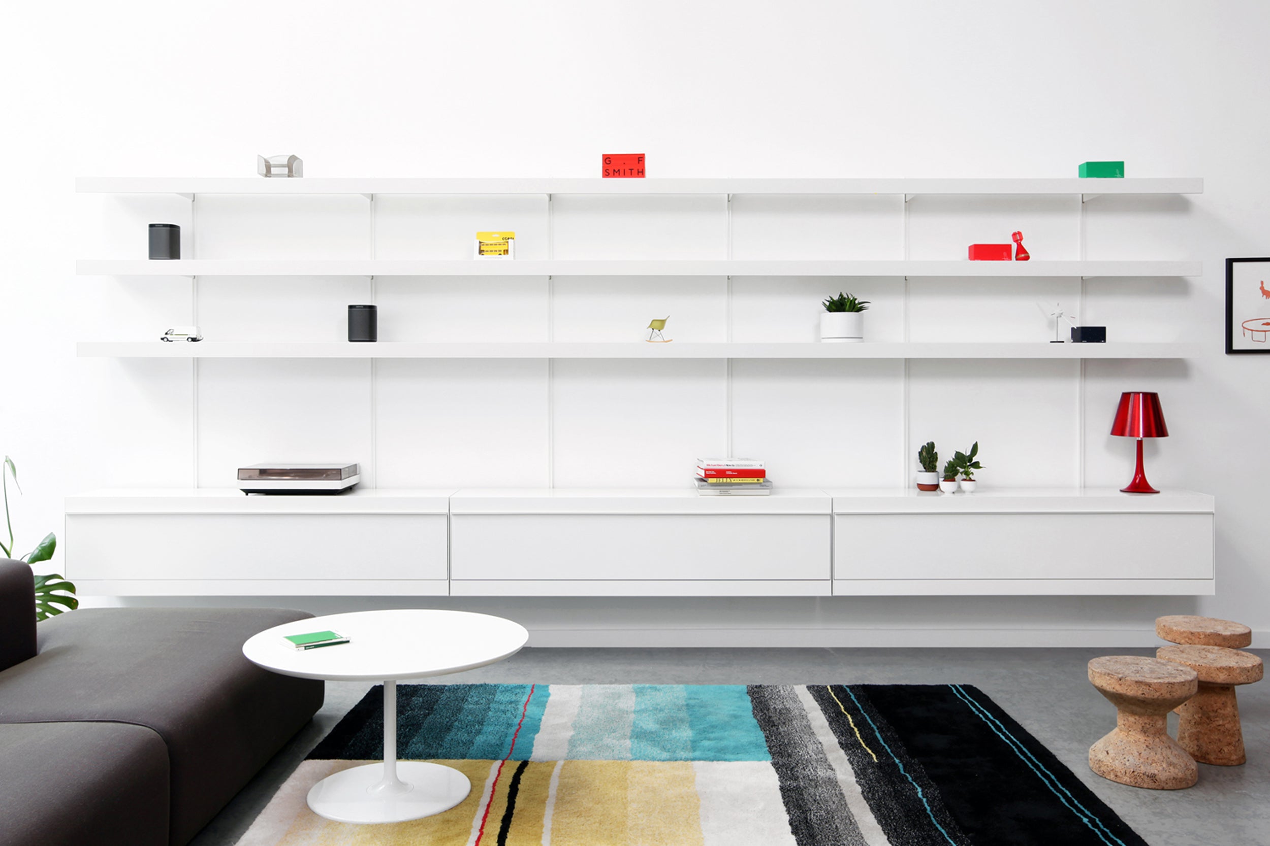 Large white wall mounted shelving system with long shelves and cabinets 