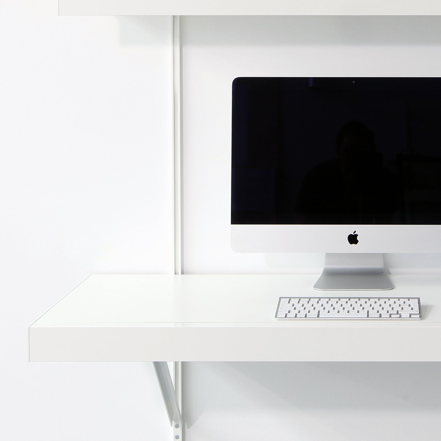 White desk with computer monitor and keyboard in a minimalistic setting