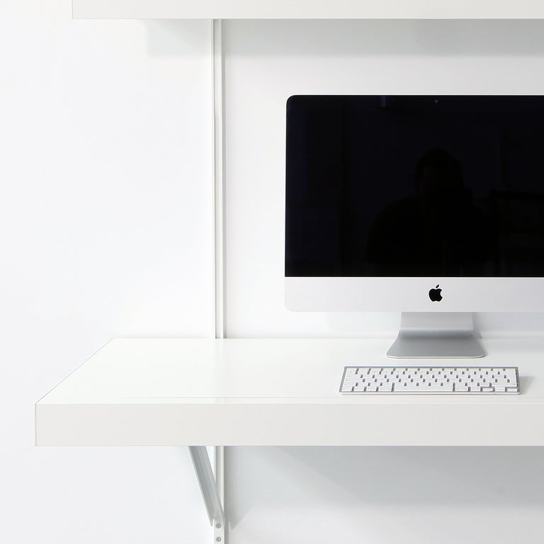 White desk with computer monitor and keyboard in a minimalistic setting