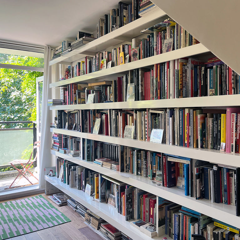 Large white book shelving system with very long wall shelves