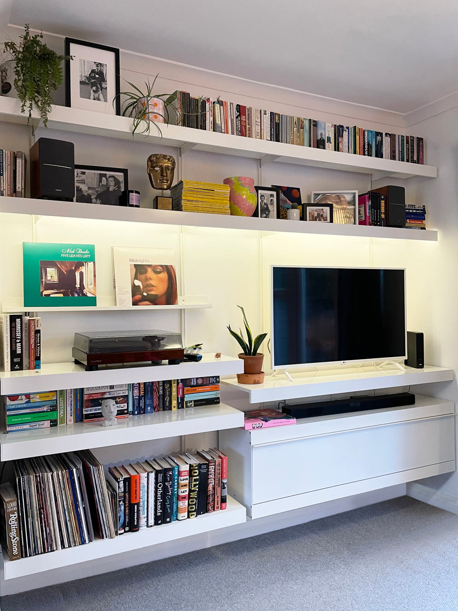 white wall mounted shelving system with vinyl storage and TV unit area