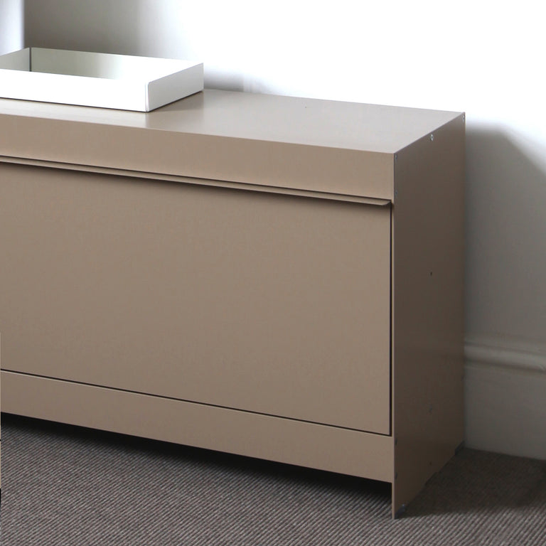 Beige tv unit with a white tray on top against a plain wall.