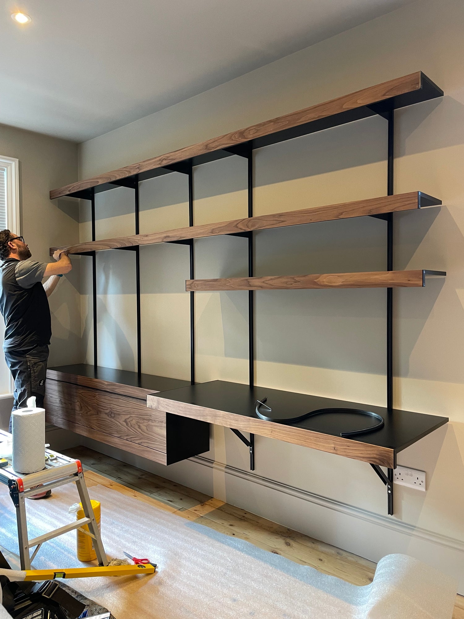 wall mounted black and walnut shelving system with large desk and long shelves by ON&ON